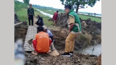 Warga membangun jembatan darurat dari bambu di lokasi jalan vital yang dijebol di Saronggi.