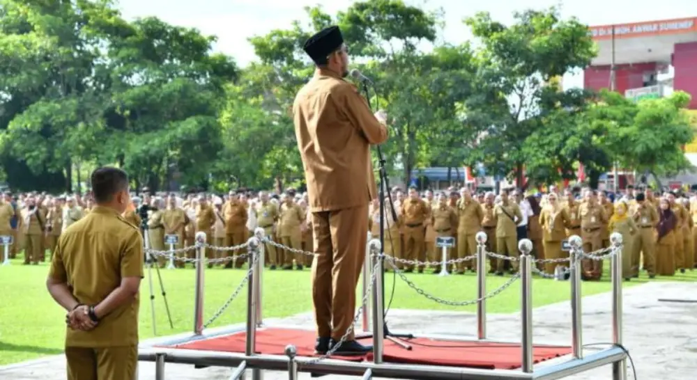 Bupati Sumenep Achmad Fauzi Wongsojudo tampak dari belakang sedang memberikan amanat di atas mimbar saat apel gabungan ASN di halaman Kantor Pemkab Sumenep. Di hadapannya, barisan ASN berseragam cokelat (khaki) mengikuti jalannya upacara dengan khidmat.