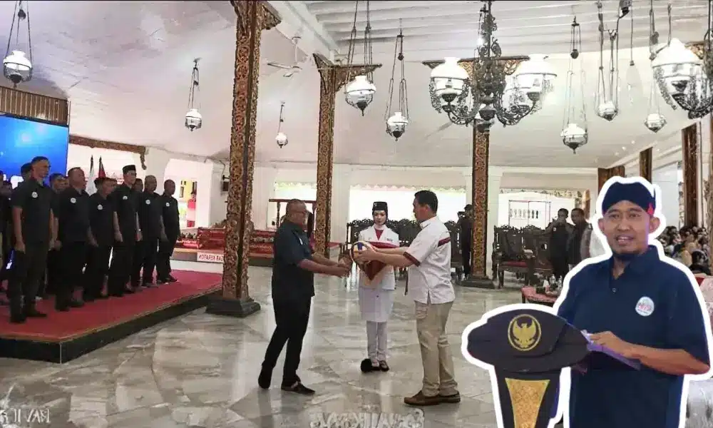 Foto suasana pelantikan pengurus PBVSI Kabupaten Sumenep masa bakti 2025–2029 di Pendopo Agung Keraton. Terlihat prosesi penyerahan pataka atau simbol organisasi di tengah ruangan berarsitektur klasik Jawa, dengan deretan pengurus berbaju hitam berdiri tegap di sisi kiri. Di bagian depan kanan, terdapat potongan gambar Bupati Achmad Fauzi Wongsojudo yang sedang memberikan sambutan.