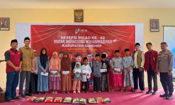 Foto bersama pengurus PC IMM Sumenep, tokoh masyarakat, kepolisian, dan anak-anak yatim di depan spanduk Resepsi Milad ke-62 IMM dengan paket bantuan beras di depan panggung.