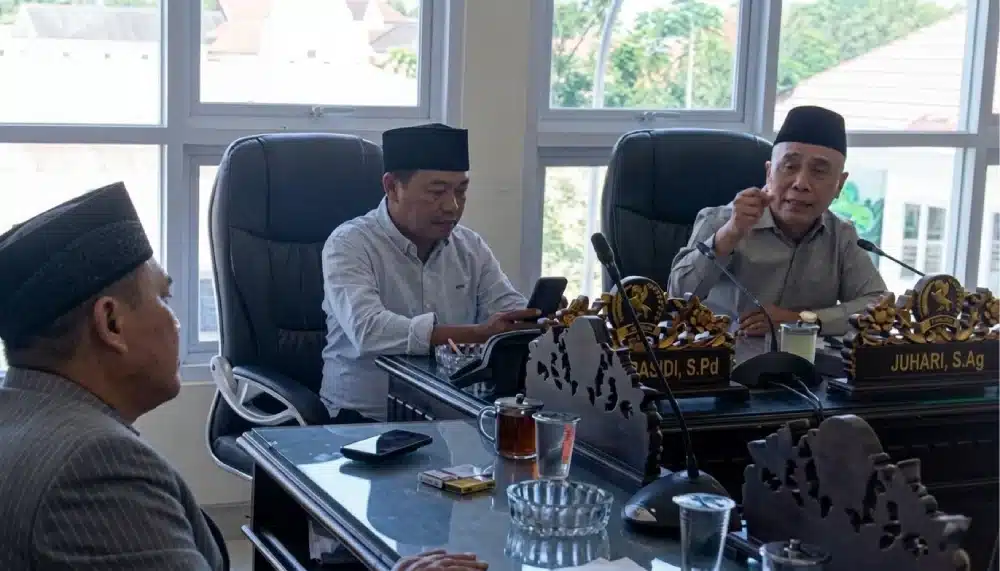 Ketua Pansus II DPRD Sumenep, H. Juhari, S.Ag (kanan), saat memimpin rapat pembahasan Raperda penyertaan modal untuk BPRS Bhakti Sumekar di Ruang Komisi II. Dalam foto terlihat suasana rapat yang serius dengan kehadiran perwakilan legislatif dan eksekutif. Di meja rapat terlihat papan nama, dokumen rapat, dan perangkat audio visual.