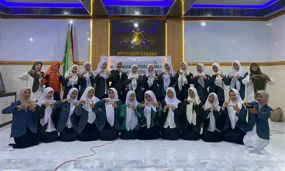 Foto bersama jajaran pengurus IPPNU Sumenep masa khidmat 2026–2028 di Aula Kantor PCNU Sumenep. Para pengurus tampak kompak mengenakan jas organisasi berwarna hijau tua dan biru, serta jilbab putih, sambil memperagakan simbol tangan berbentuk huruf 'B' sebagai simbol tagline 'IPPNU BISA'. Di latar belakang, terdapat logo emas dengan tulisan "PENGURUS CABANG" dan lambang organisasi.