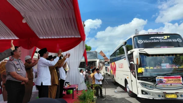 Wakil Bupati Sumenep dan jajaran pejabat melambaikan tangan melepas keberangkatan bus jemaah haji di depan tenda merah putih.