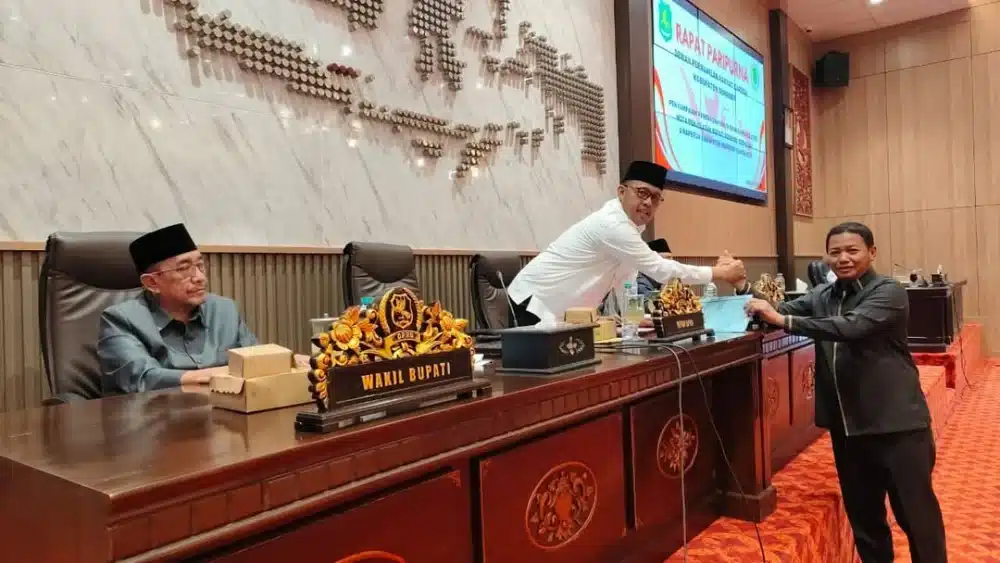 Jabat tangan antara pimpinan DPRD Sumenep dan perwakilan fraksi saat penyerahan dokumen pandangan umum dalam rapat paripurna pembahasan tiga Raperda strategis 2026.