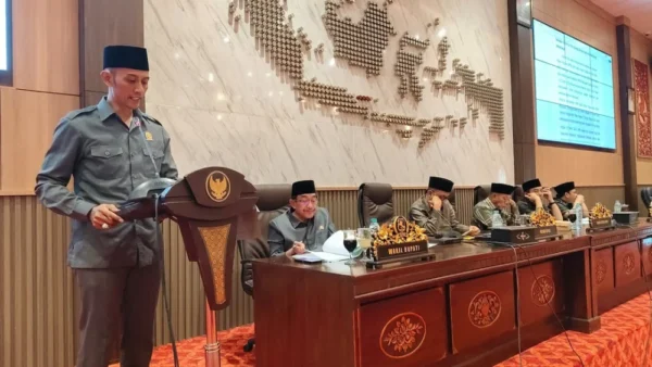 Samsiyadi, anggota DPRD Sumenep dari Fraksi NasDem, berdiri di podium membacakan laporan hasil reses di samping meja pimpinan rapat.
