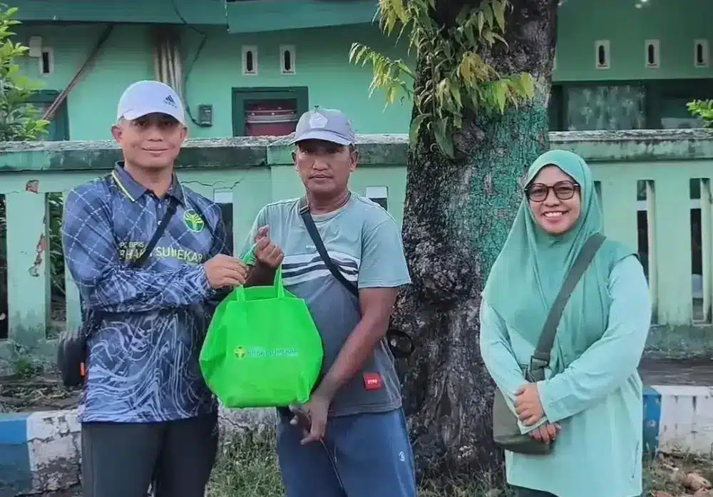 Direktur Utama BPRS Bhakti Sumekar Hairil Fajar menyerahkan bantuan sembako dalam tas hijau kepada seorang warga saat kegiatan Jumat Berkah di Sumenep.