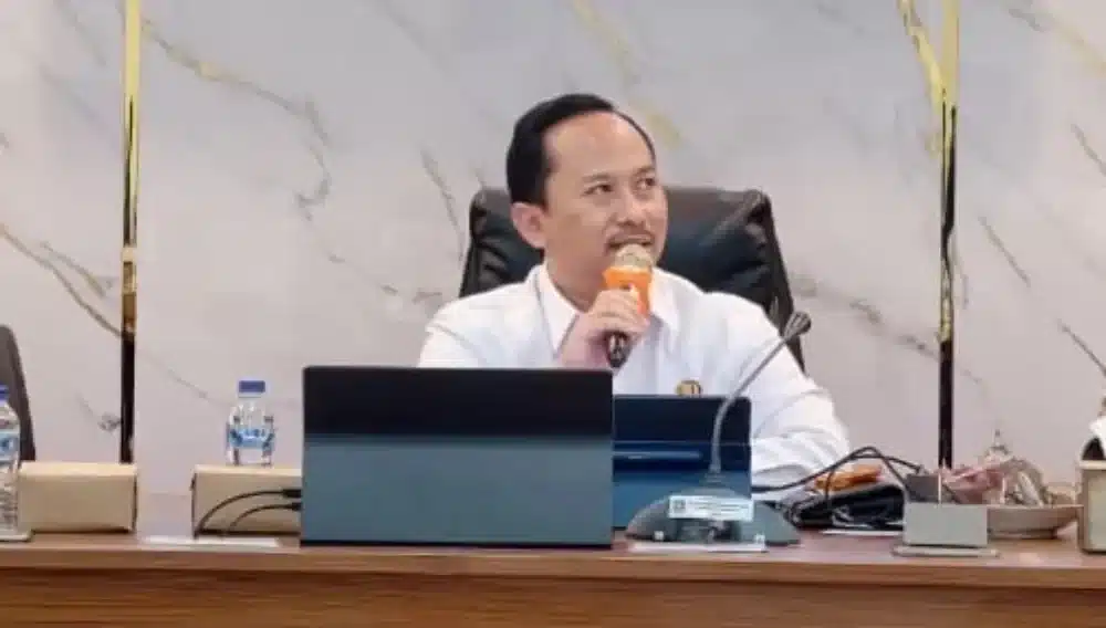 Kepala Bappeda Sumenep, Arif Firmanto, sedang berbicara menggunakan mikrofon di meja rapat saat memaparkan program penguatan kewirausahaan dan ketenagakerjaan daerah.